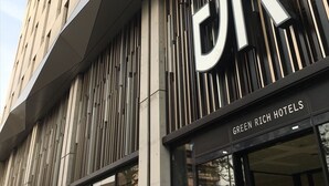 A modern building with a prominent 'DR' sign and 'GREEN RICH HOTELS' text.