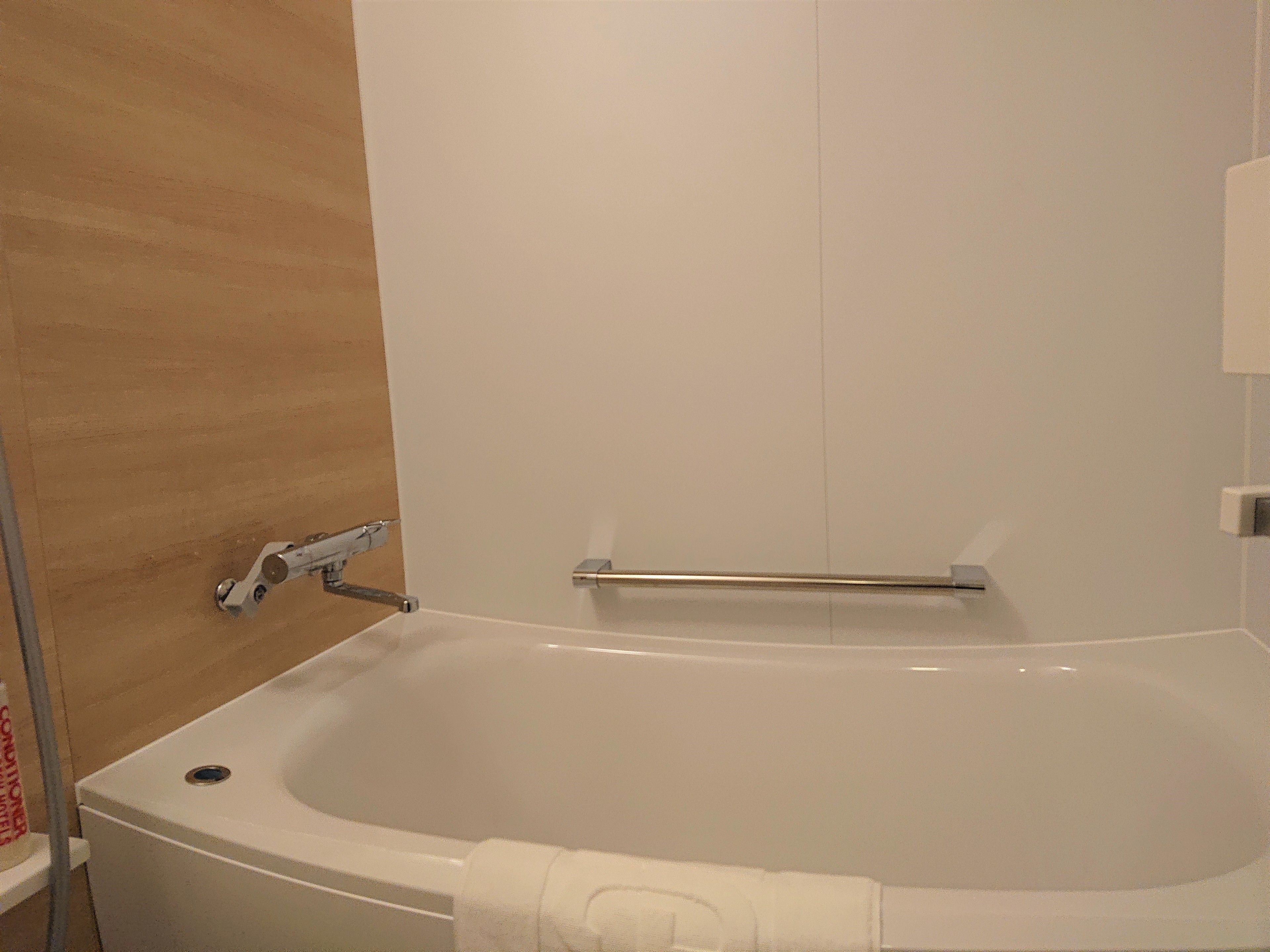 A bathroom with a white bathtub, a towel rack, and a shower area.
