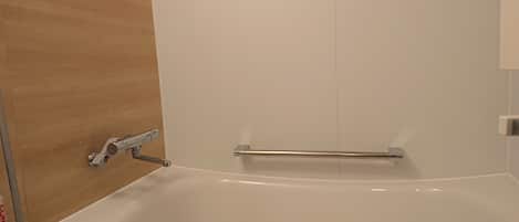 A bathroom with a white bathtub, a towel rack, and a shower area.