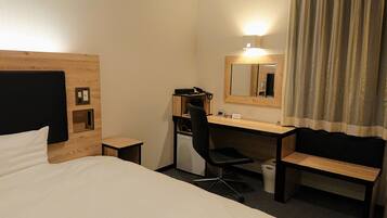 A hotel room with a bed, a desk, a chair, a mirror, and a curtain.