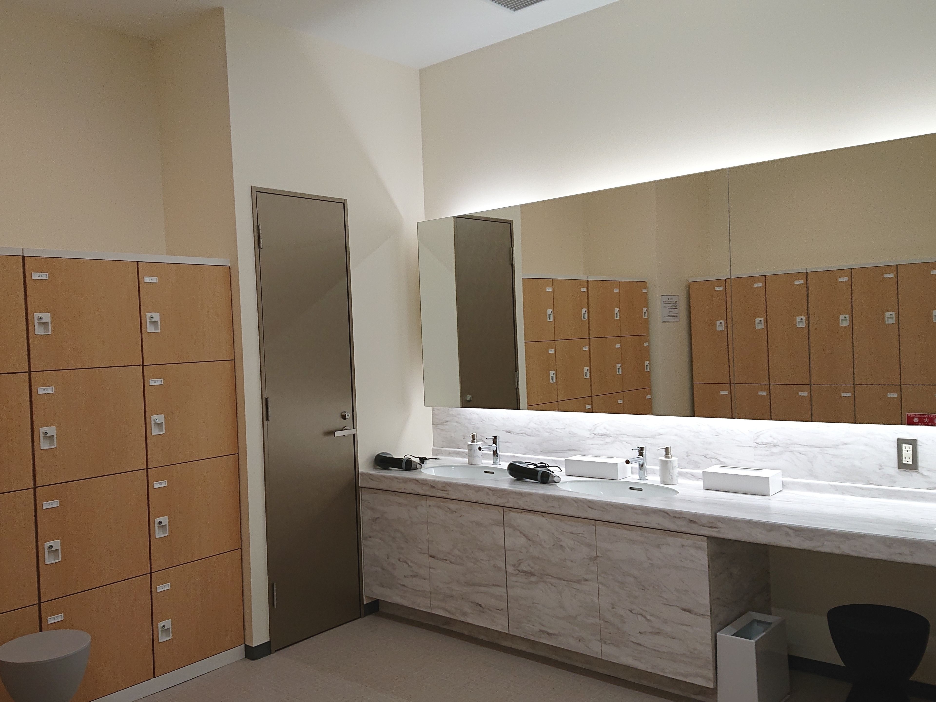 A bathroom with lockers, a sink, and a mirror.