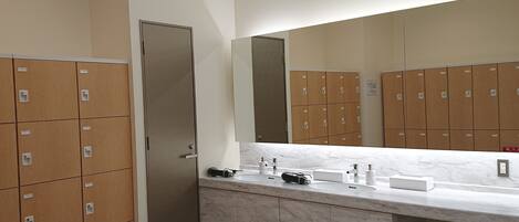 A bathroom with lockers, a sink, and a mirror.