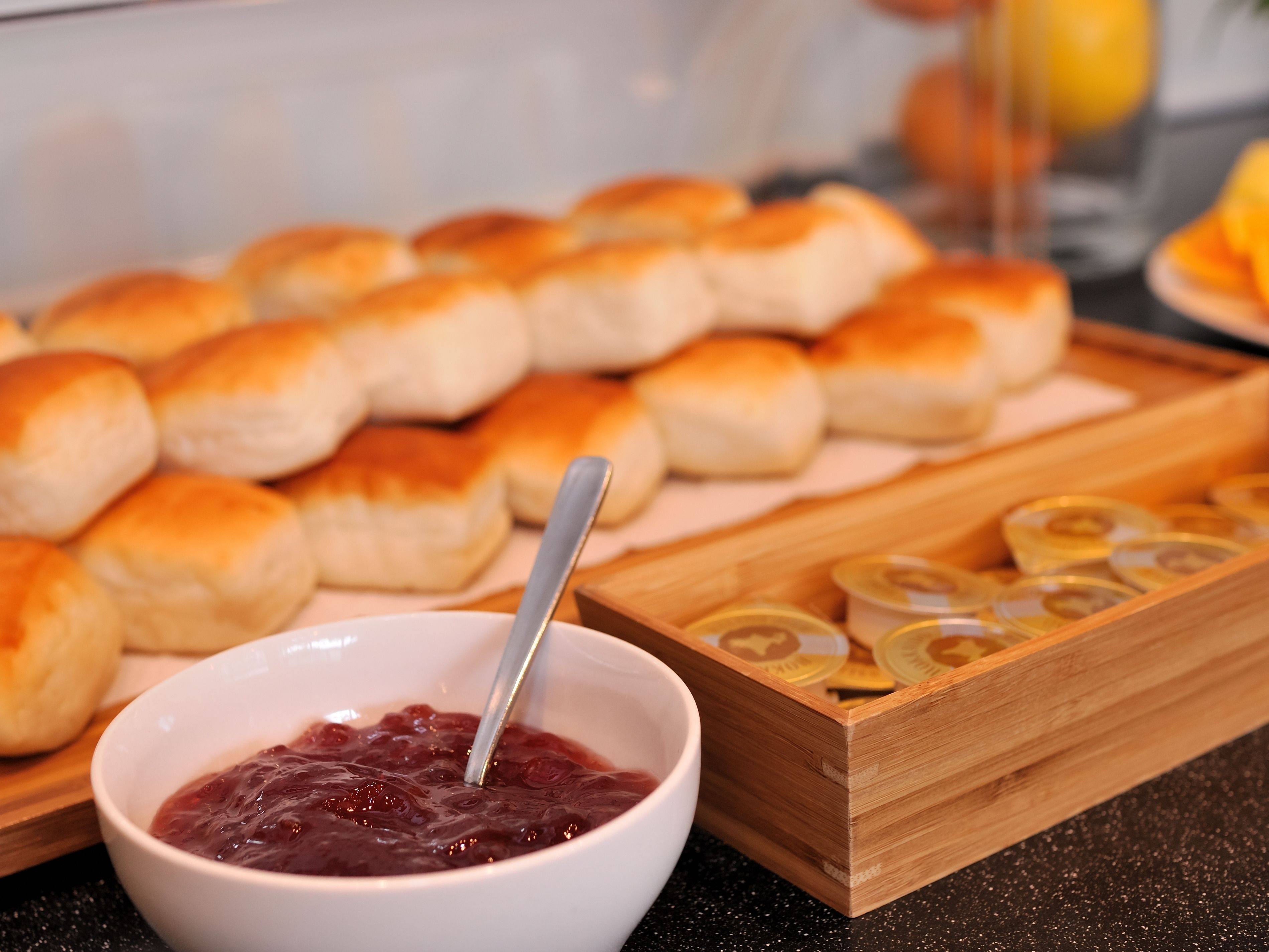 A tray of freshly baked rolls and a bowl of jam.