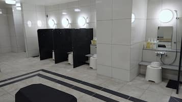 A modern restroom with multiple sinks, black partitions, and a large mirror.