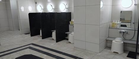 A modern restroom with multiple sinks, black partitions, and a large mirror.