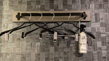 A wall-mounted drying rack with multiple hooks and a bottle of hand sanitizer.