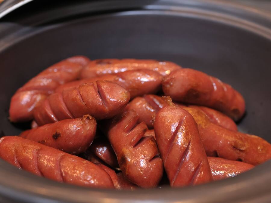 A close-up of cooked sausages in a black container.
