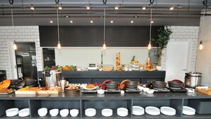A buffet setup with various dishes, a coffee machine, and a fruit display.