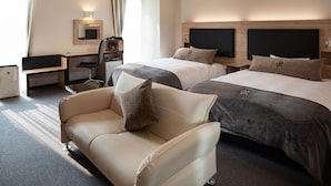 A hotel room with two beds, a desk, a chair, and a sofa.