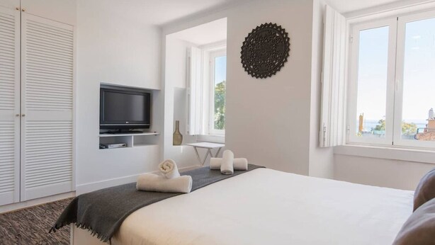 Hotelkamer met een bed, een televisie, een raam met uitzicht en een decoratief wandobject.