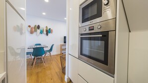 Een moderne keuken met roestvrijstalen apparatuur, een eethoek met blauwe stoelen en houten vloeren.