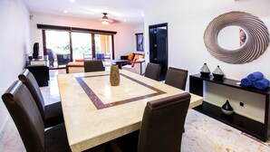 Un comedor con una mesa de mármol, sillas oscuras y una pieza decorativa moderna en la pared.