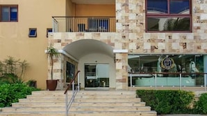 Un edificio con fachada de piedra, un balcón y una escalera que conduce a la entrada.