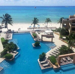 A resort with a central pool, lounge areas, and a beach view. - Large ground-floor a 2-bedroom condo with a balcony at ELFARO by DPM (Playa del Carmen)