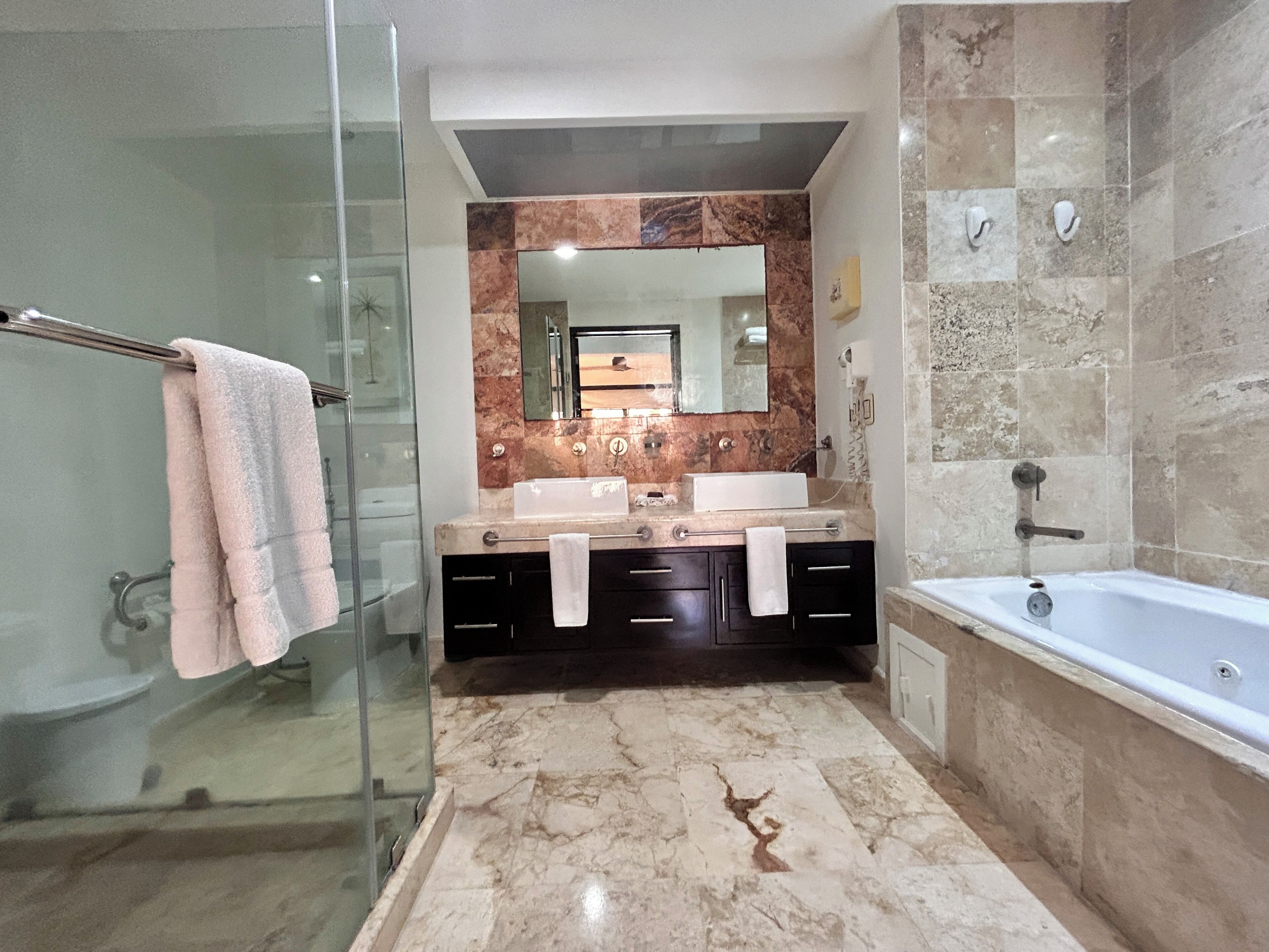 A modern bathroom with a glass shower enclosure, a double sink vanity, and a standalone bathtub.
