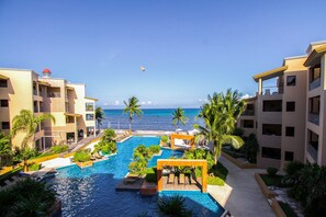 A resort with a large swimming pool, palm trees, and a view of the ocean.