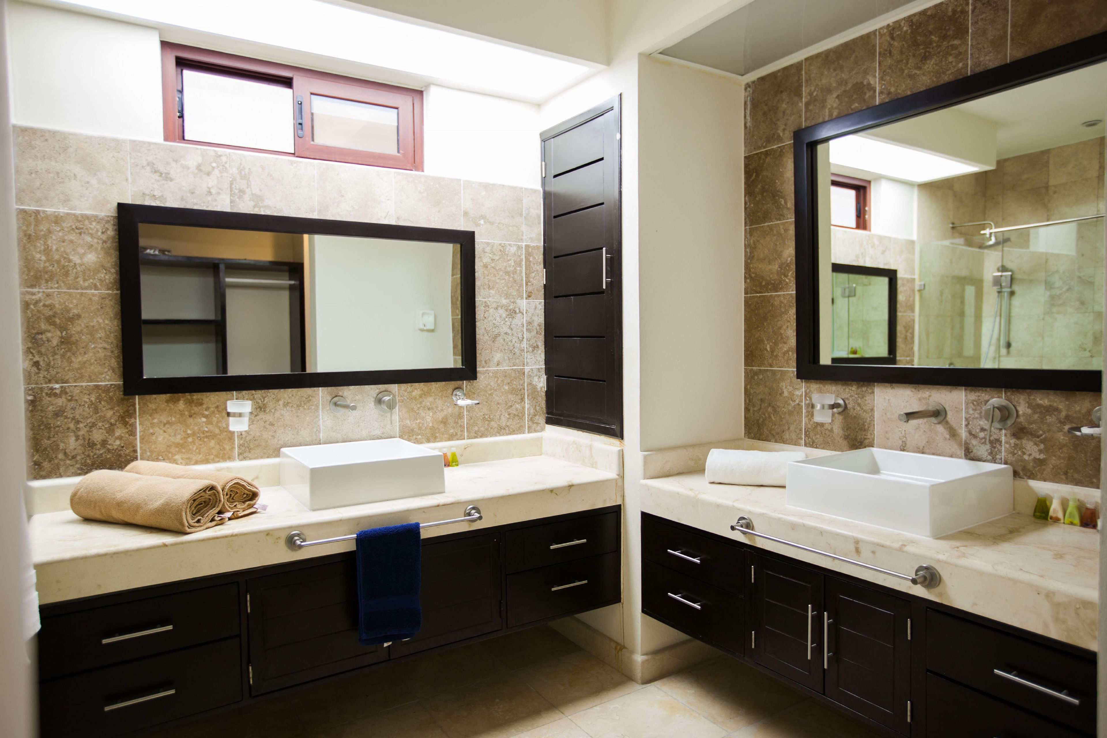 Een moderne badkamer met twee wastafels, donkere kastjes en een grote spiegel.