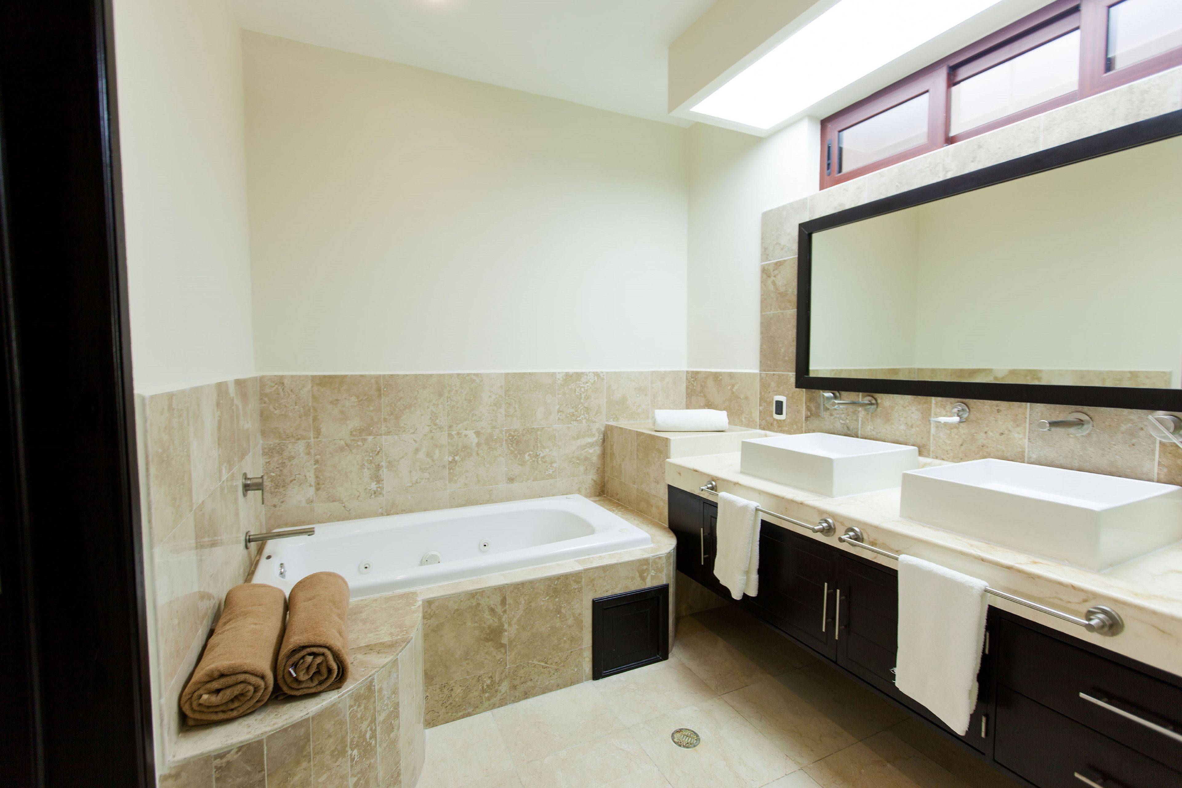 Une salle de bain moderne avec une baignoire, deux lavabos et un grand miroir.