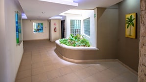 En hall med en böjd blomlåda fylld med växter, en brandsläckare och en tavla på väggen.