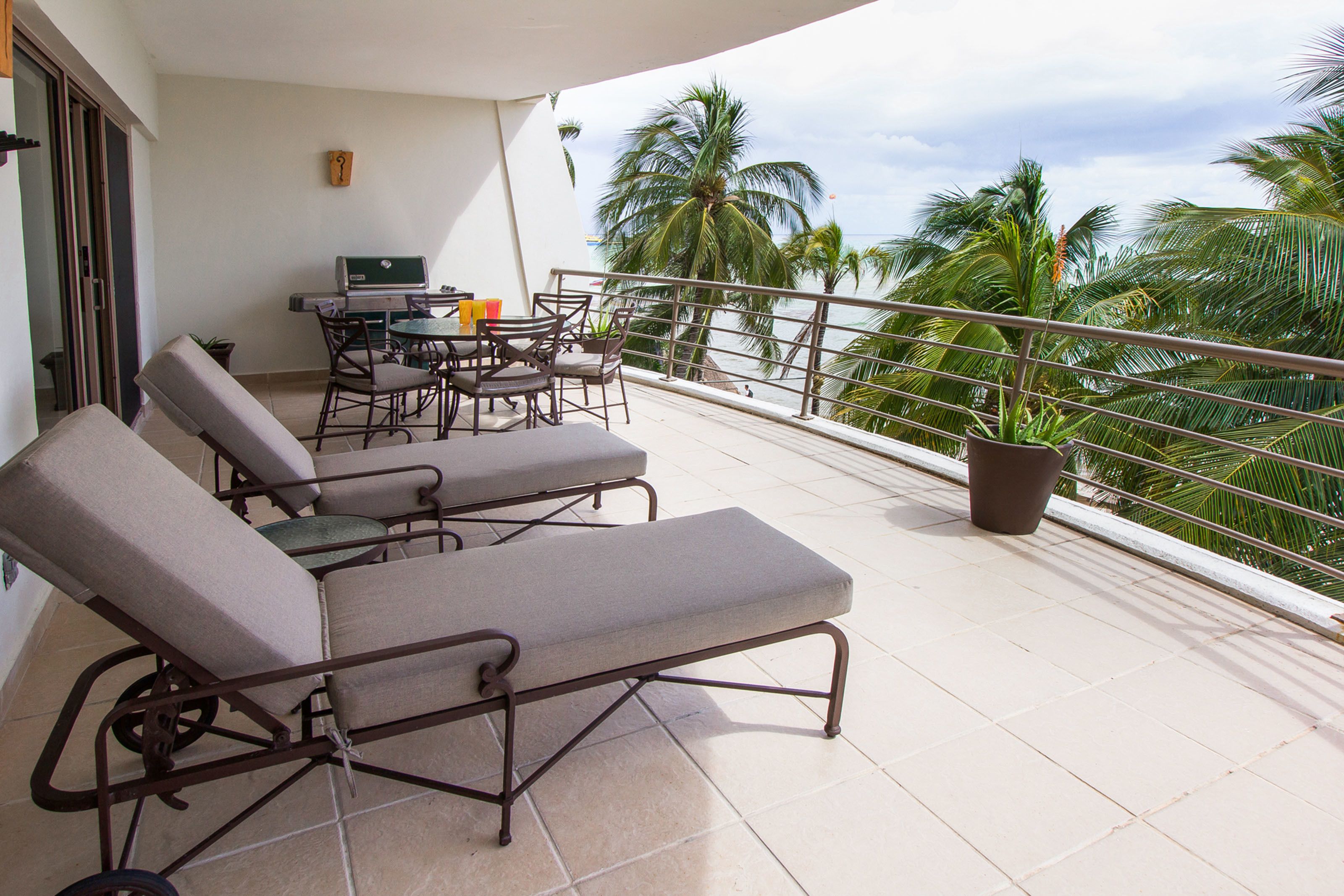 A balcony with two lounge chairs, a small table, and a grill.