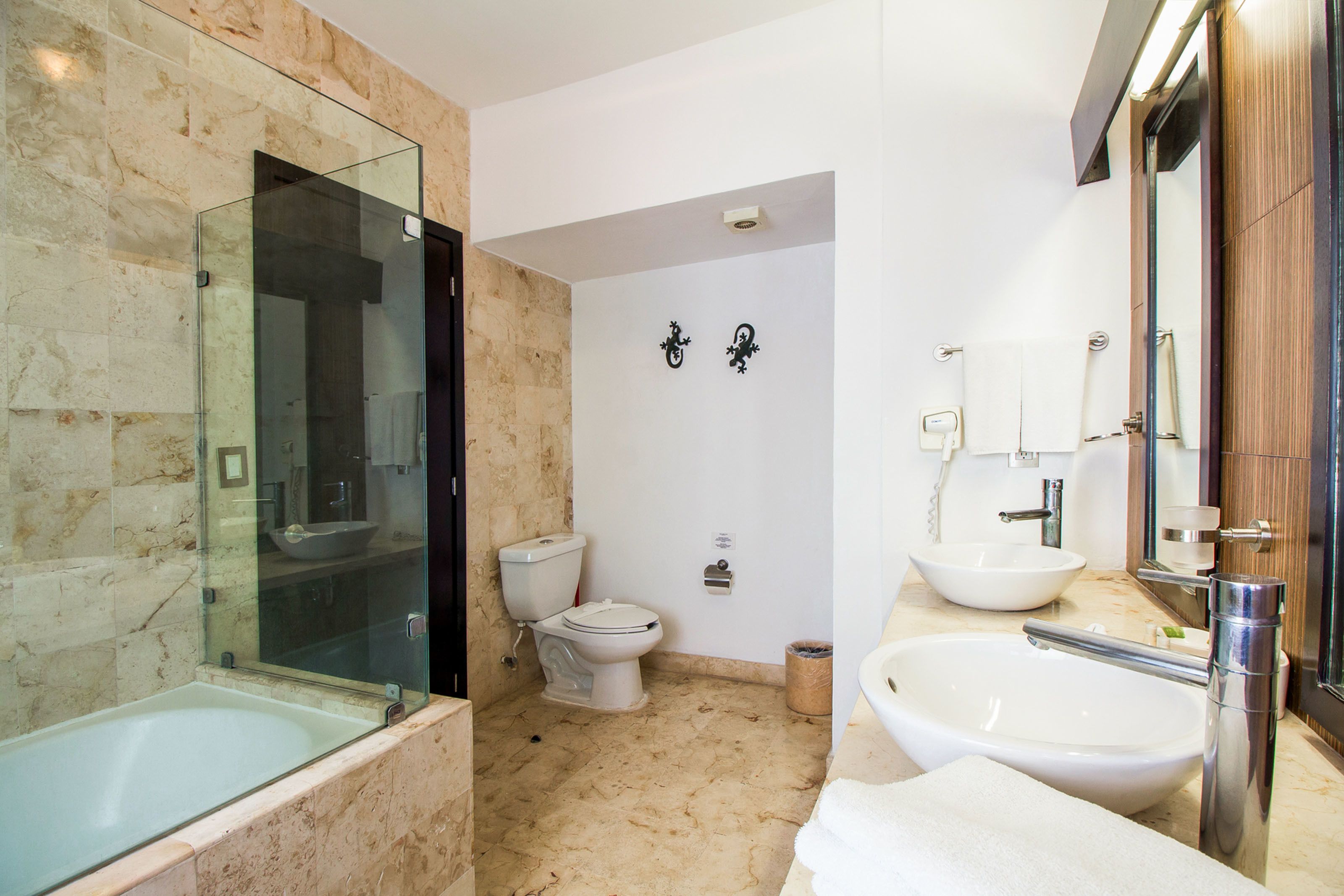 Een badkamer met een douchecabine, een toilet en twee wastafels.