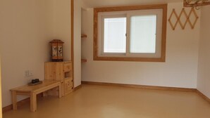 A room with a wooden bench, a cabinet with a decorative item, and a window with a wooden frame.