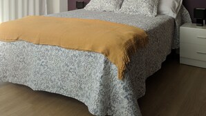 A bedroom with a bed, a bedside table, a lamp, and a window with curtains. - Villa on the coast Santander (Monte - Santander)