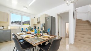 Een moderne keuken met een eettafel gedekt voor vier personen, een koelkast en een trap naar een hoger niveau.