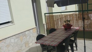 An outdoor patio with a table and chairs, a potted plant, and a large umbrella. - GROUND FLOOR APARTMENT WITH CALA GONONE VERANDA AT 30 MT FROM THE SEA (Cala Gonone)