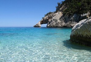 Un paisaje costero con agua turquesa cristalina, un acantilado rocoso y una formación rocosa natural.