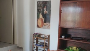 A dining area with a round table covered by a tablecloth with a marine theme, a wooden bookshelf, and a wall-mounted poster. - GROUND FLOOR APARTMENT WITH CALA GONONE VERANDA AT 30 MT FROM THE SEA (Cala Gonone)