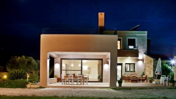 Une maison moderne à deux étages, dotée d’un patio couvert et d’un espace salon extérieur.