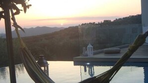 Un hamac au bord d’une piscine, avec vue sur le coucher de soleil.