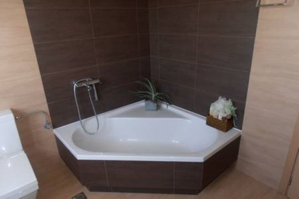 A modern bathroom with a freestanding bathtub, a showerhead, and a small plant.