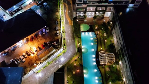 A nighttime aerial view of a hotel with a swimming pool, parking area, and adjacent buildings. - Skypod Residence (Puchong)