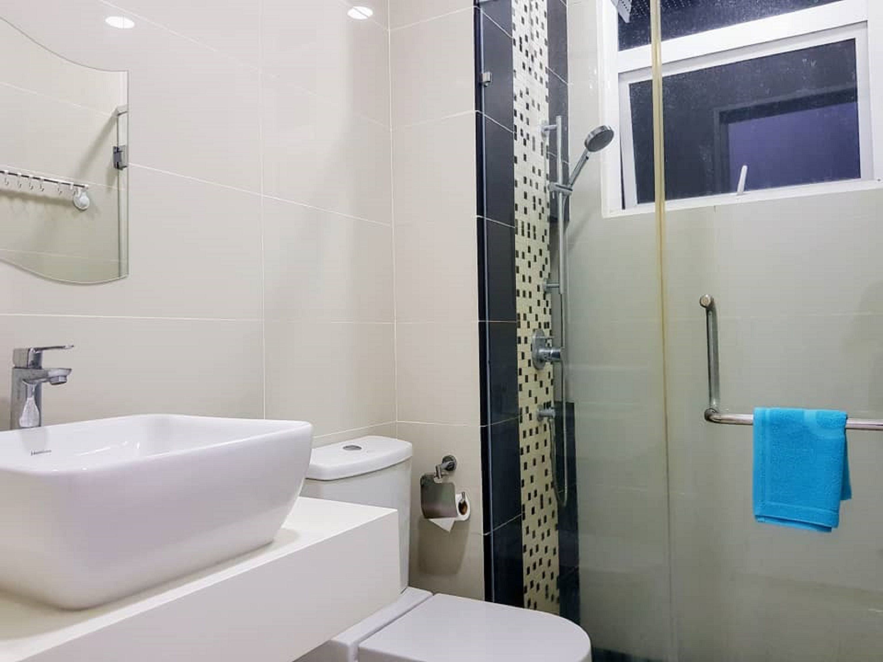 A modern bathroom with a white sink, toilet, and shower area.