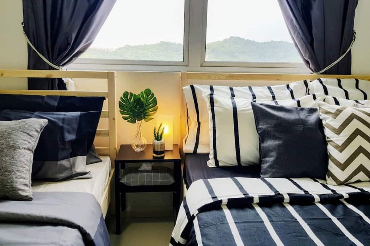 Ein Zimmer mit zwei Betten, einem kleinen Tisch mit Pflanze und Blick ins Freie.