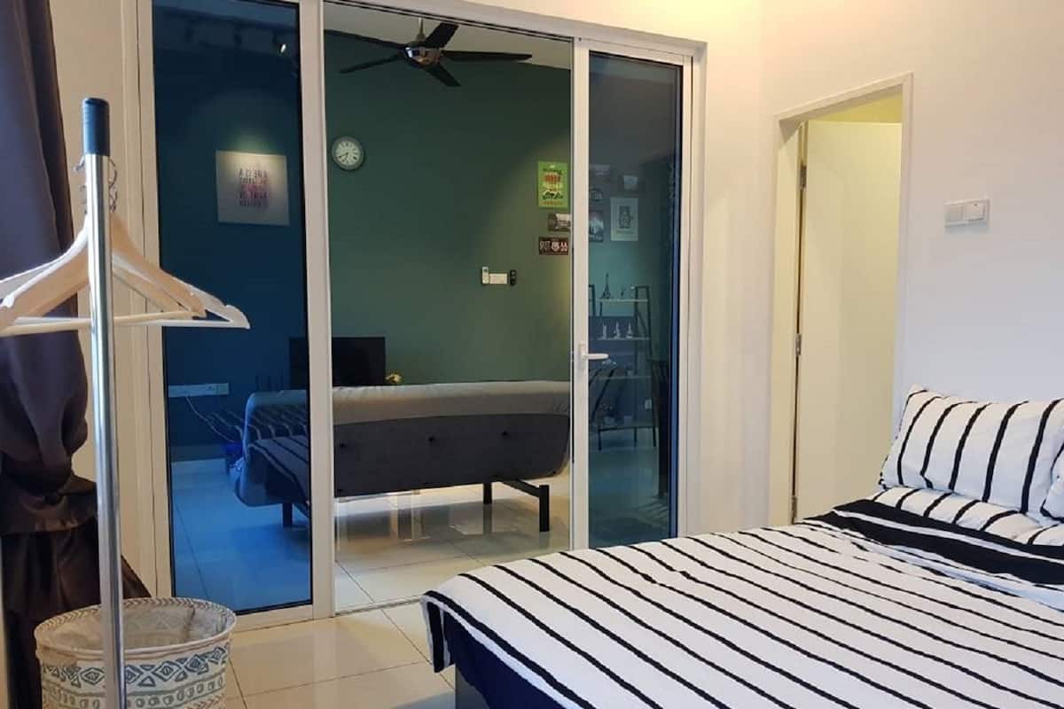 Ein Schlafzimmer mit einem Bett, einem Deckenventilator, einer Schiebetür, die auf einen Balkon führt, und einem kleinen Teppich.
