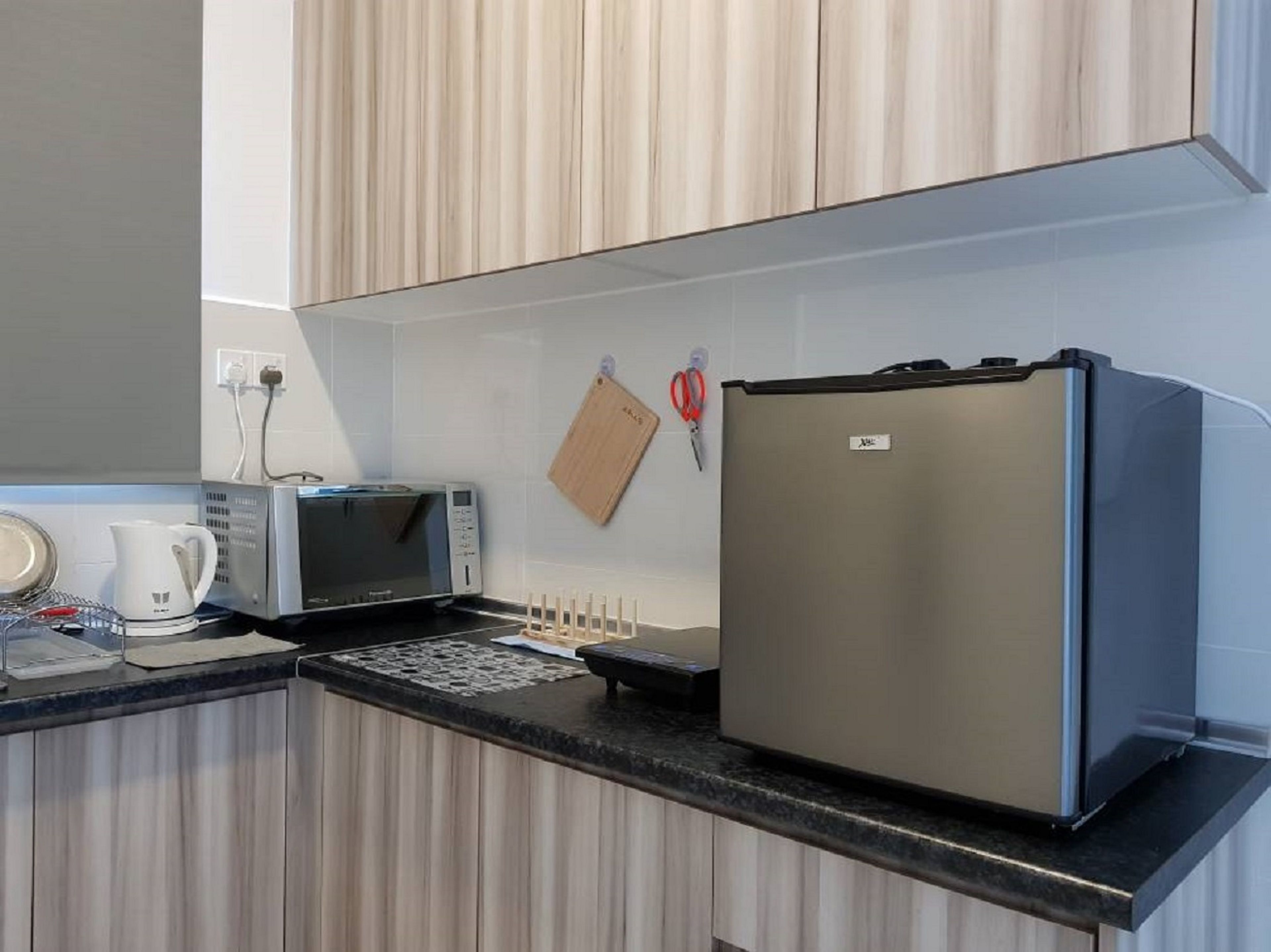 A modern kitchen with a built-in microwave, a refrigerator, and a coffee maker on the counter.