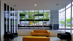 A modern lobby with large windows, a yellow sofa, and black armchairs. - Skypod Residence (Puchong)