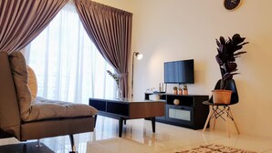 A modern living room with a sofa, a flat-screen TV, a plant, and a clock on the wall. - Skypod Residence (Puchong)