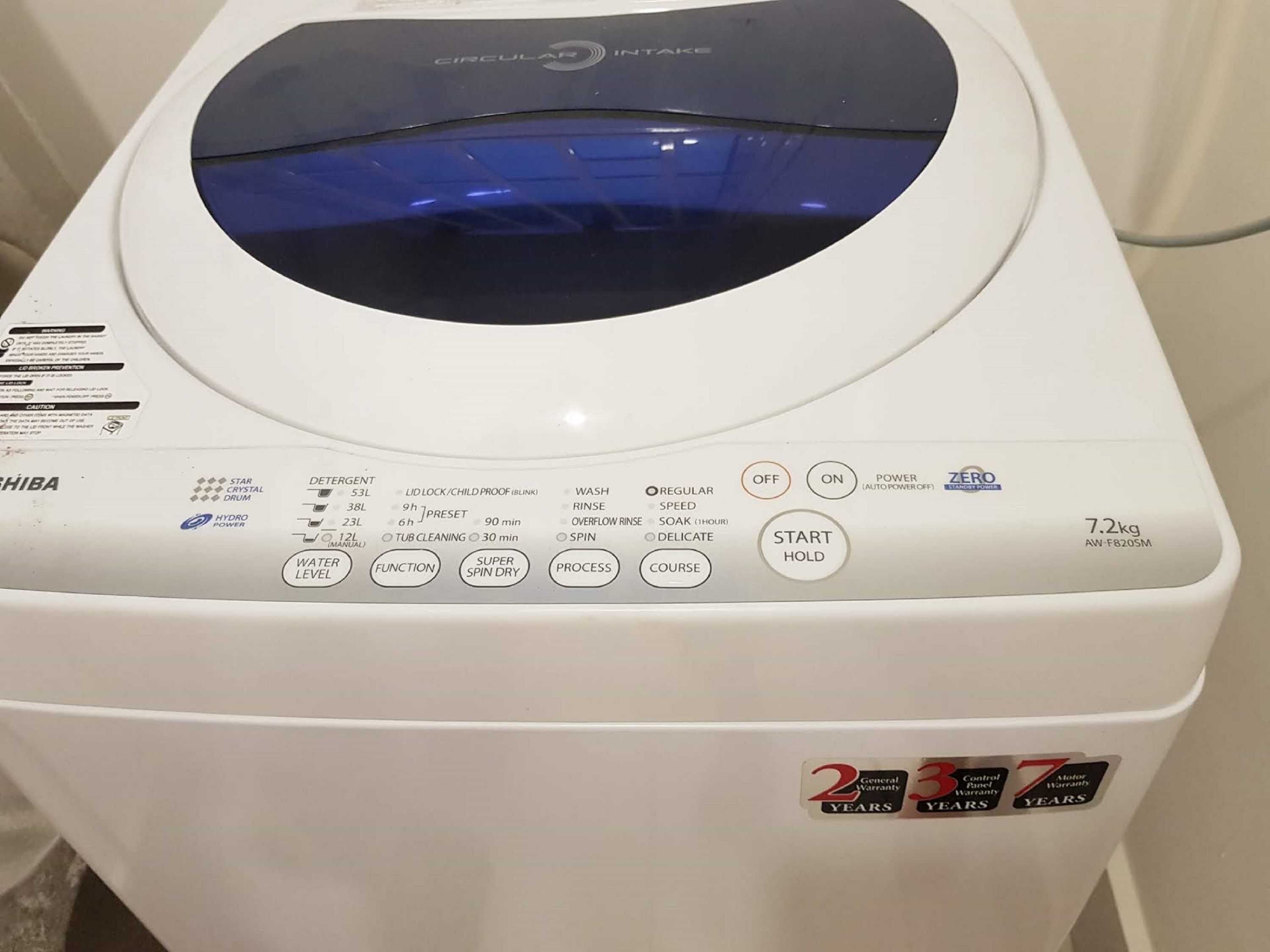 A front view of a white washing machine with control panel, brand name, and weight.