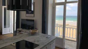 A modern kitchen with a large window overlooking a beach.