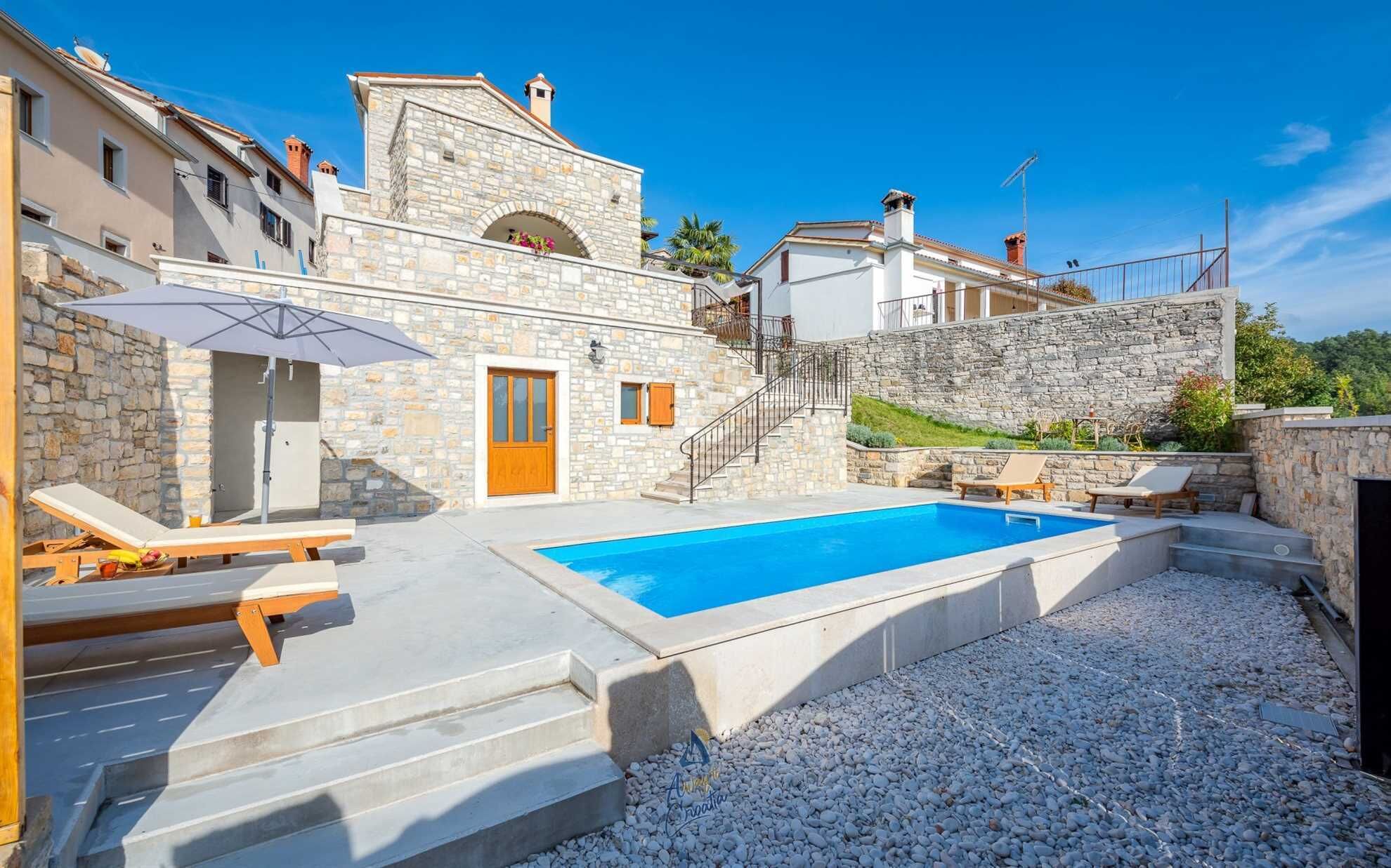A pool area with stone buildings, a wooden door, and a clear blue sky.