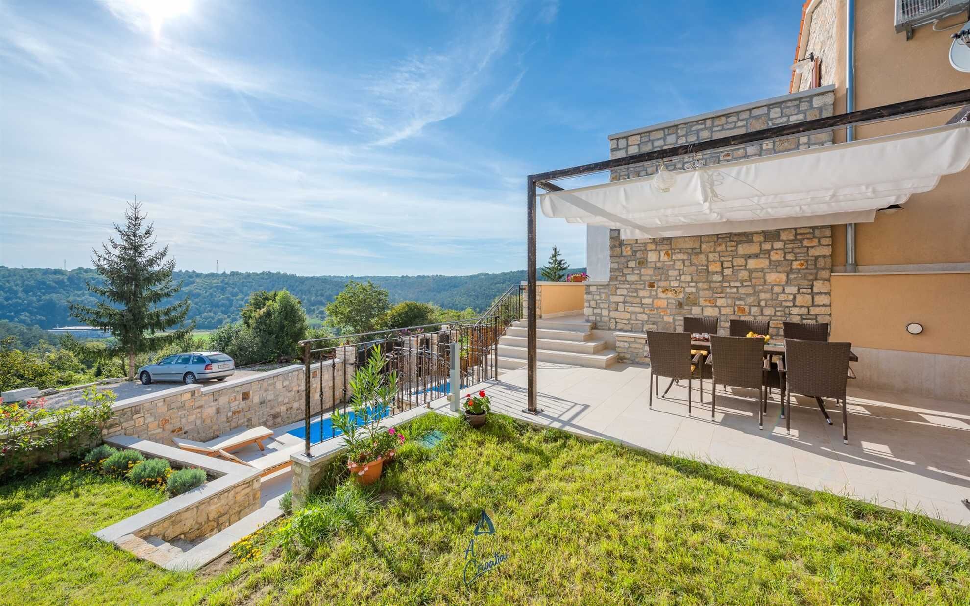 A villa with a stone exterior, a pool, outdoor seating, and a view of the surrounding landscape.