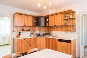 Una cocina compacta con armarios de madera, una campana extractora negra y un lavavajillas.