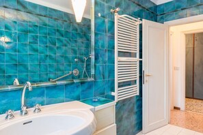 A bathroom with a bathtub, a white towel rack, and a shower area.