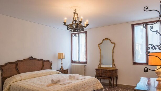 Una camera da letto con un grande letto, un lampadario, uno specchio e una cassettiera.