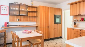 Una cucina compatta con mobili in legno, forno a incasso e zona pranzo con tavolo e sedie.