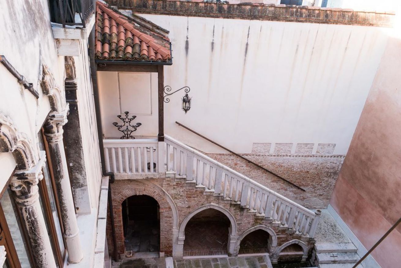 Eine Treppe mit weißen Geländern führt zu einem Balkon mit einem Ziegeldach.